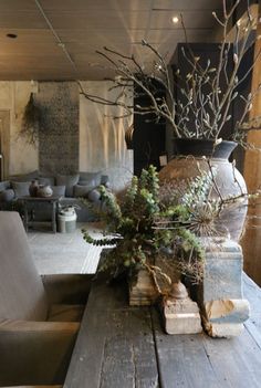 a wooden table topped with a vase filled with flowers and greenery next to a couch