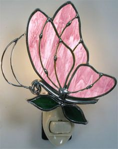 a pink stained glass butterfly sitting on top of a light switch