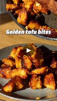 two plates filled with fried food on top of a wooden table next to a frying pan