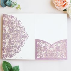 an open wedding card with purple lace on the front and back, sitting next to flowers