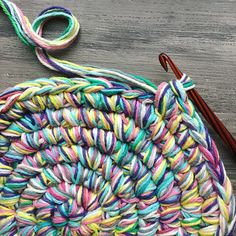 a crochet basket with yarn and a knitting needle on the table next to it