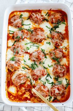 a casserole dish with meatballs and cheese in it on a white towel