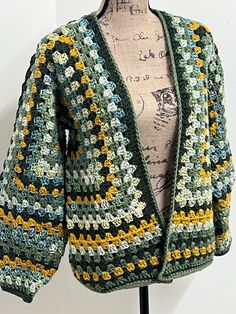 a crocheted green and yellow jacket on a mannequin's head