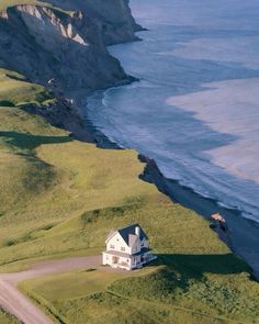 an aerial view of a house on the side of a cliff overlooking the ocean and cliffs