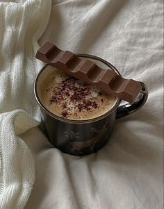 a cup of hot chocolate sitting on top of a bed