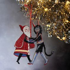 an ornament hanging from a christmas tree with two people dressed as santa claus