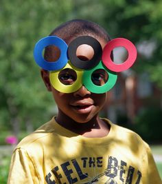 a young boy with four colored circles on his eyes and one is wearing a yellow t - shirt