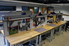 a work station with lots of tools on the wall and desks in front of it