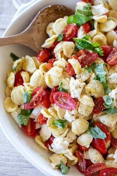 a pasta salad with tomatoes, mozzarella and basil