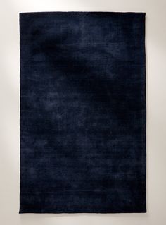 a large blue rug is hanging up on the wall in front of a white wall