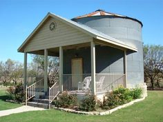 a small house with a large water tank on the front porch and stairs leading up to it