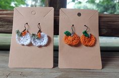 two small crocheted pumpkins are hanging from earrings