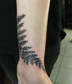 a person with a tattoo on their arm that has a fern leaf design on it