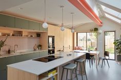 an open kitchen and dining room area with skylights above the countertop, along with bar stools