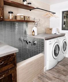 a washer and dryer in a room with wooden shelves on the wall above them