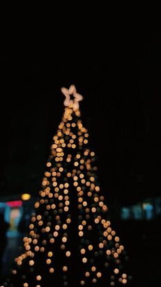 a lit up christmas tree in the dark with lights on it's top and bottom