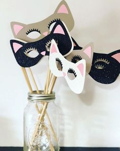 three masks on sticks in a mason jar