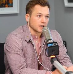 a man sitting in front of a microphone with ear buds on his ears and wearing headphones