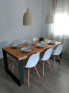 a wooden table with white chairs and plates on it