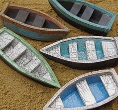 four small boats sitting on top of sand next to each other in different colors and sizes