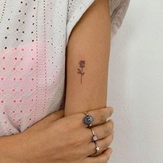 a woman's arm with a small rose tattoo on the left side of her arm