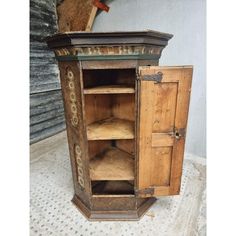 an old wooden cabinet with two doors and shelves on the bottom, next to a wall