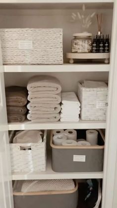 an organized closet with white baskets and towels