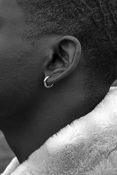 a close up of a person with an earring on their head and wearing a fur coat