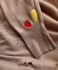 a sweater with a red and yellow dot on it