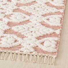 an area rug with fringes on top of it and a wooden floor in the background