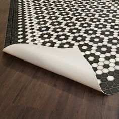 a black and white rug with hexagonal tiles on the floor next to it