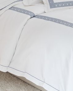 a bed with white sheets and blue trimmings on the pillowcase is shown