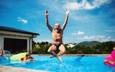 a man jumping into a swimming pool with other people