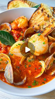 a bowl of seafood soup with bread on the side