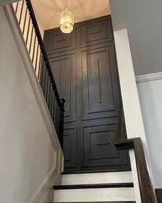 the stairs are painted black and white with wood paneling on each side, along with a chandelier