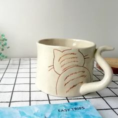 a coffee mug sitting on top of a table next to a blue piece of paper