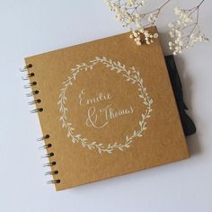 a wedding guest book with a floral wreath on it next to some baby's breath flowers