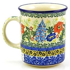 a blue and white coffee mug with flowers on it's side, sitting in front of a white background