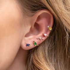 a woman's ear with three different colored stones on it and one is in the middle