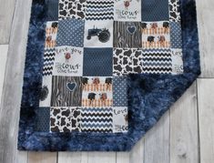 a blue and white blanket on top of a wooden floor with an animal print design