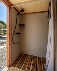 a bathroom with a shower and wooden flooring in the corner next to a window