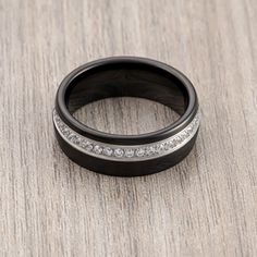 two black rings with white diamonds sitting on top of a wooden table