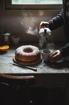 a person pours coffee into a cup next to a bundt cake on a wooden table