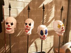 several masks are lined up on poles in front of a brick wall