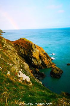 the ocean is blue and green as it sits on top of a hill near some cliffs