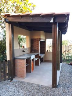 an outdoor kitchen is shown in the middle of a gravel area with a grill and sink