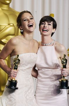 two women standing next to each other in front of an oscar statue