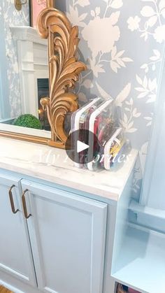 a mirror sitting on top of a white cabinet next to a shelf filled with books