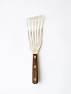 a white spatula with wooden handles on a white surface, showing the bottom part of the utensil