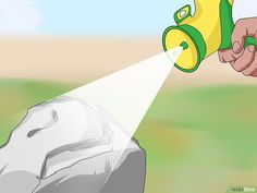 a hand holding a yellow and green watering can over a rock with a white light coming from it